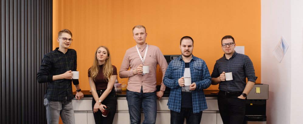 Several individuals stand united in front of a wall, reflecting a moment of togetherness and interaction among the group.